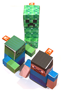 Photo of a green pixelated monster, a man and a zombie all made from paper