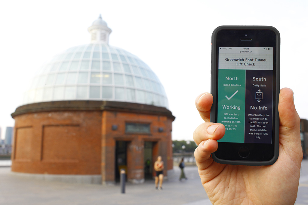 Smartphone displaying lift status app in front of Greenwich Foot Tunnel entrance. App reads ' North, Island Gardens, Working; South, Cutty Sark, No Info'